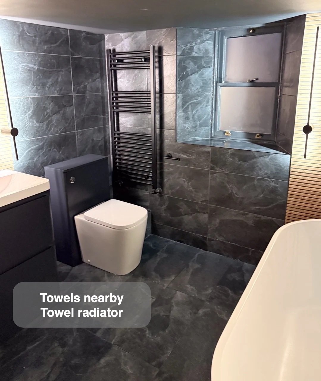 Towel radiator between window and bathing area