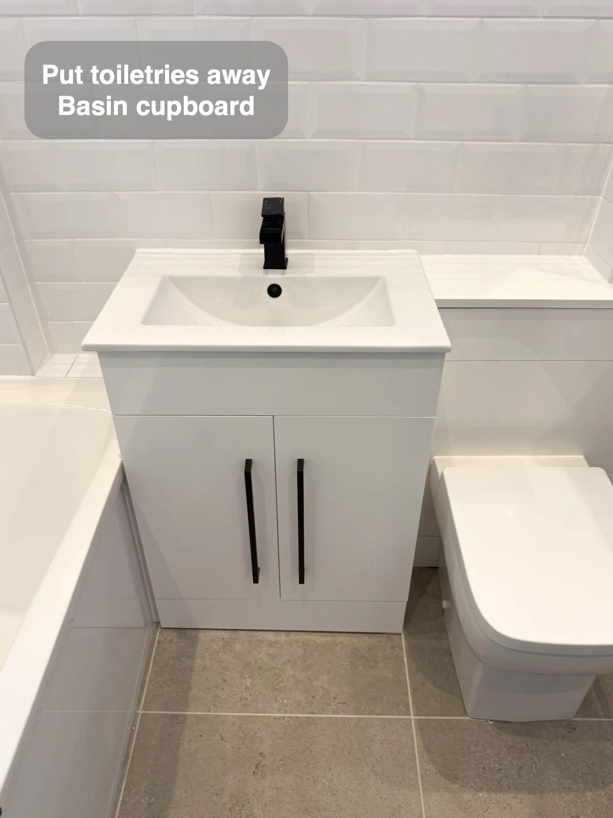 White basin cupboard beside back-to-wall toilet
