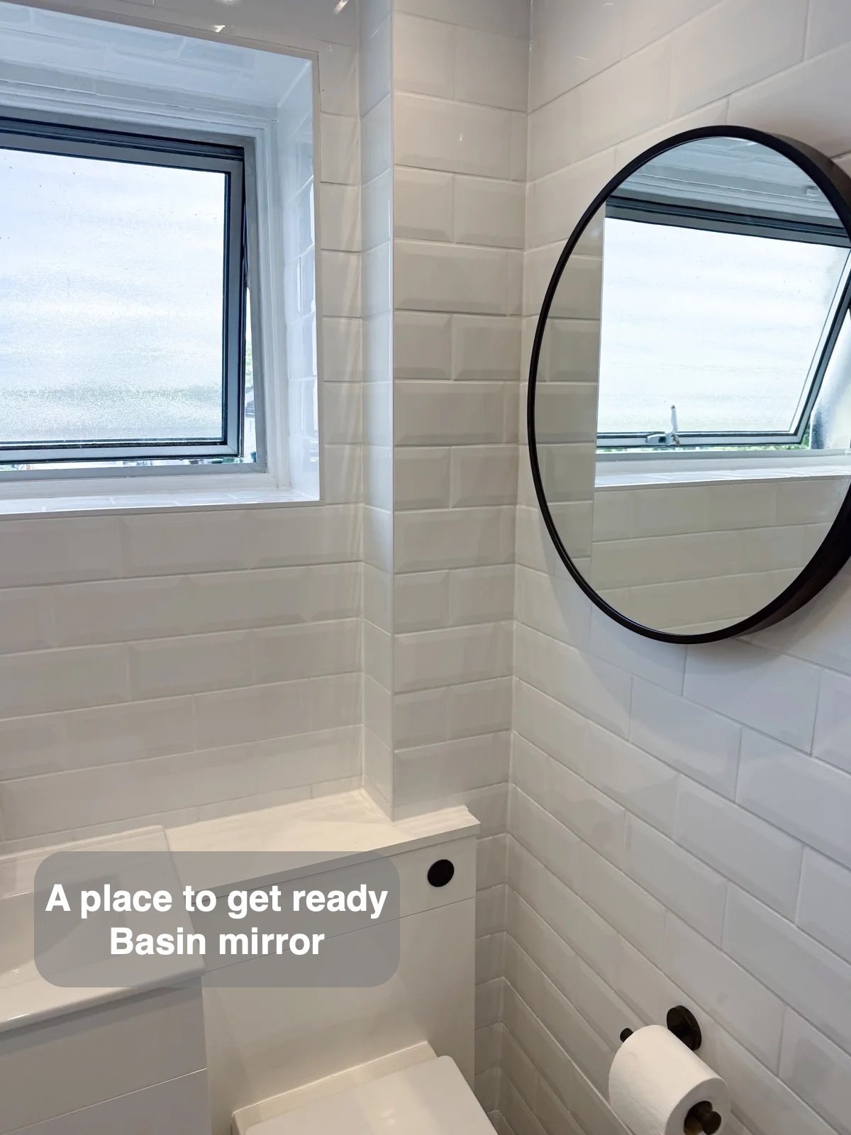 Round black mirror beside window