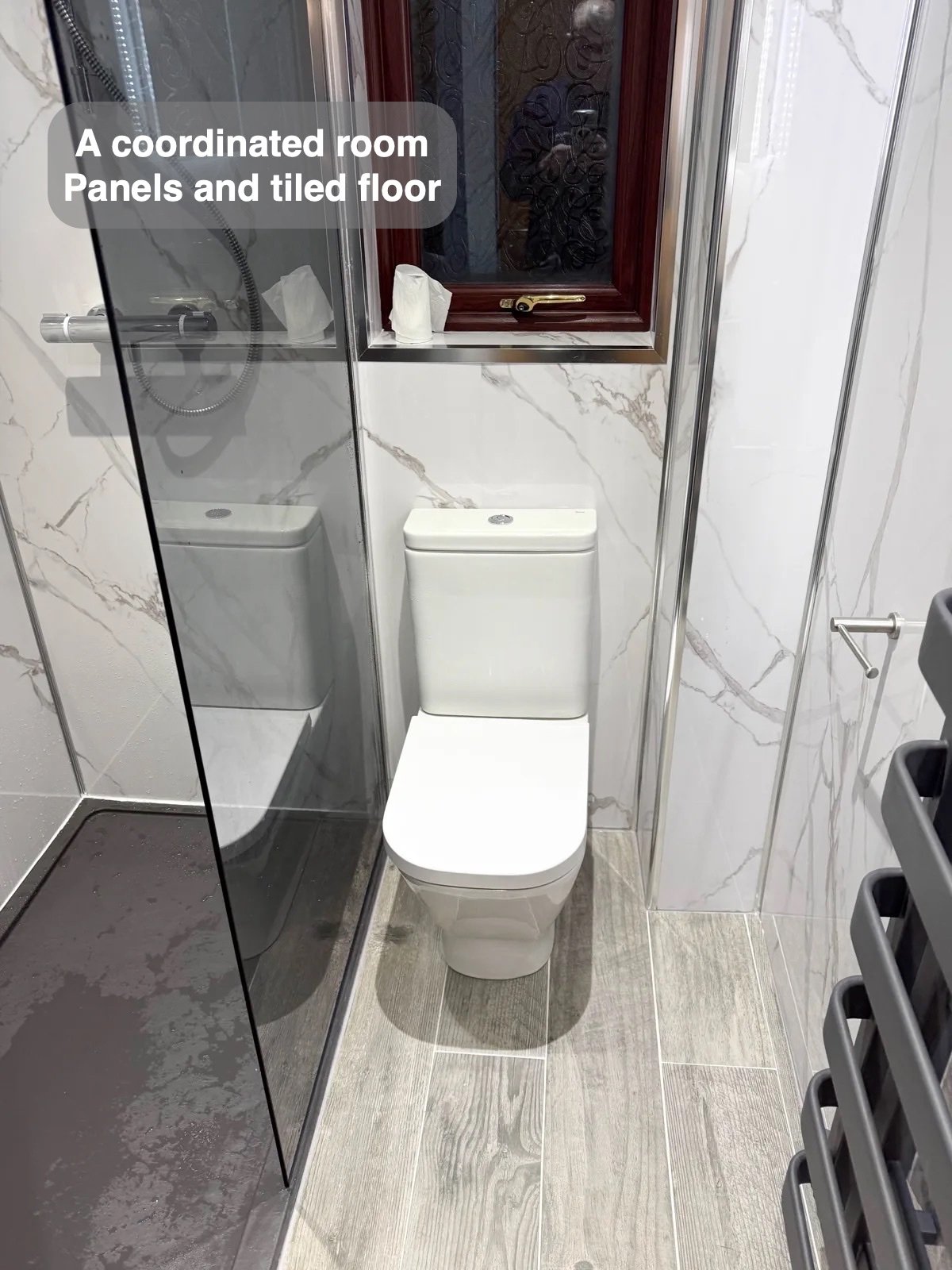 Toilet and tiled floor beside shower