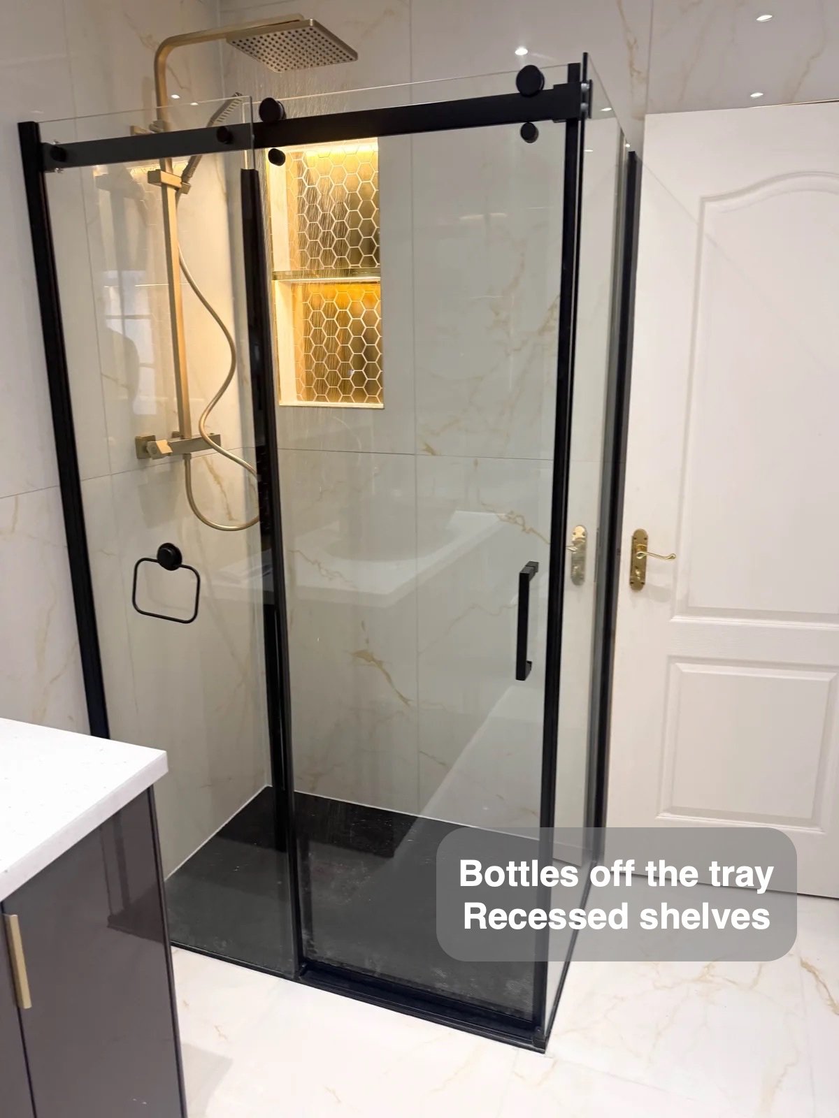 Black shower enclosure with gold fittings and recesses