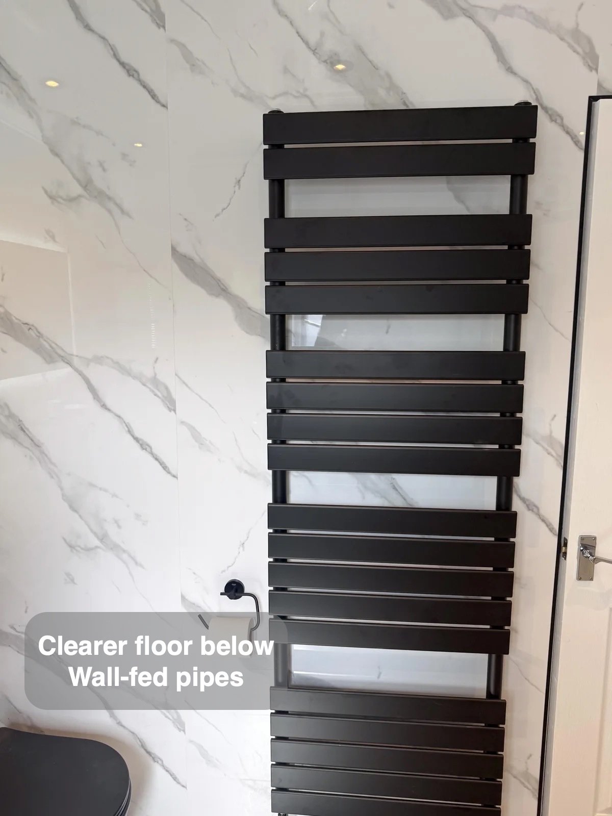 Black towel radiator with wall-fed pipes