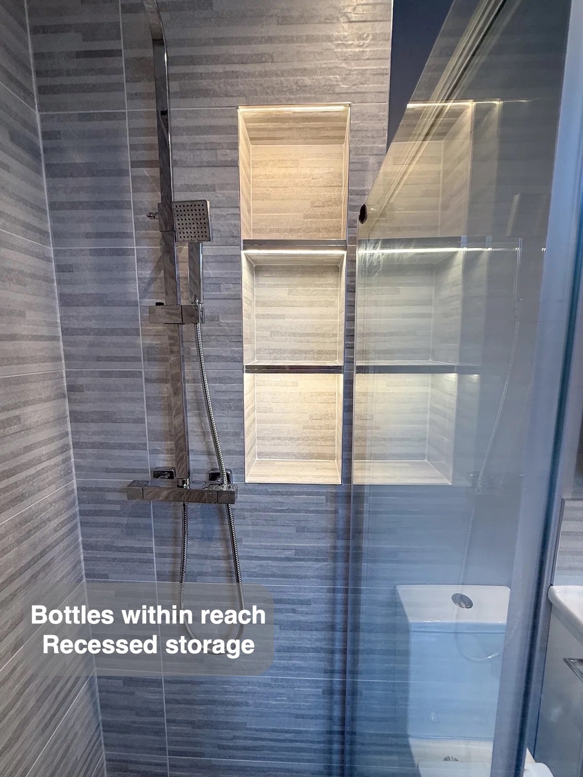 Shower handset beside illuminated wall recesses