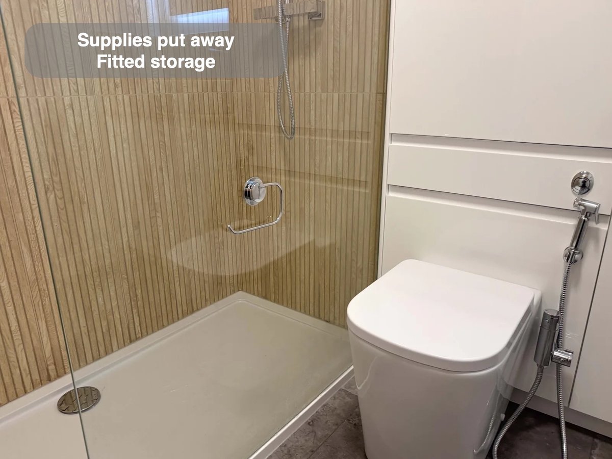 Shower and toilet beside tall fitted furniture