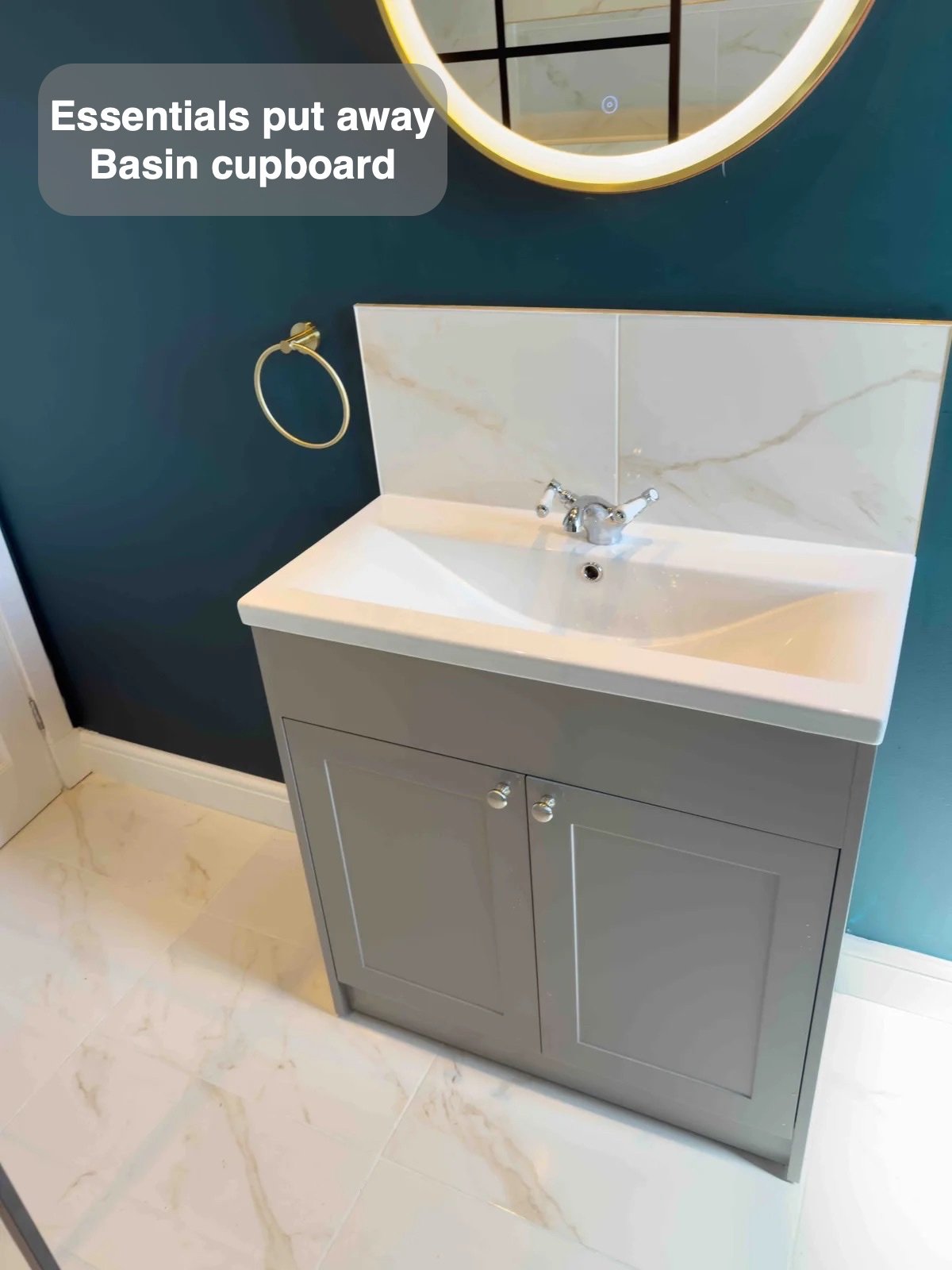 Basin vanity beneath round illuminated mirror