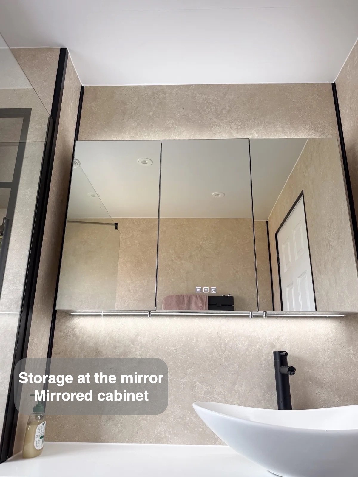 Illuminated mirror cabinet above basin
