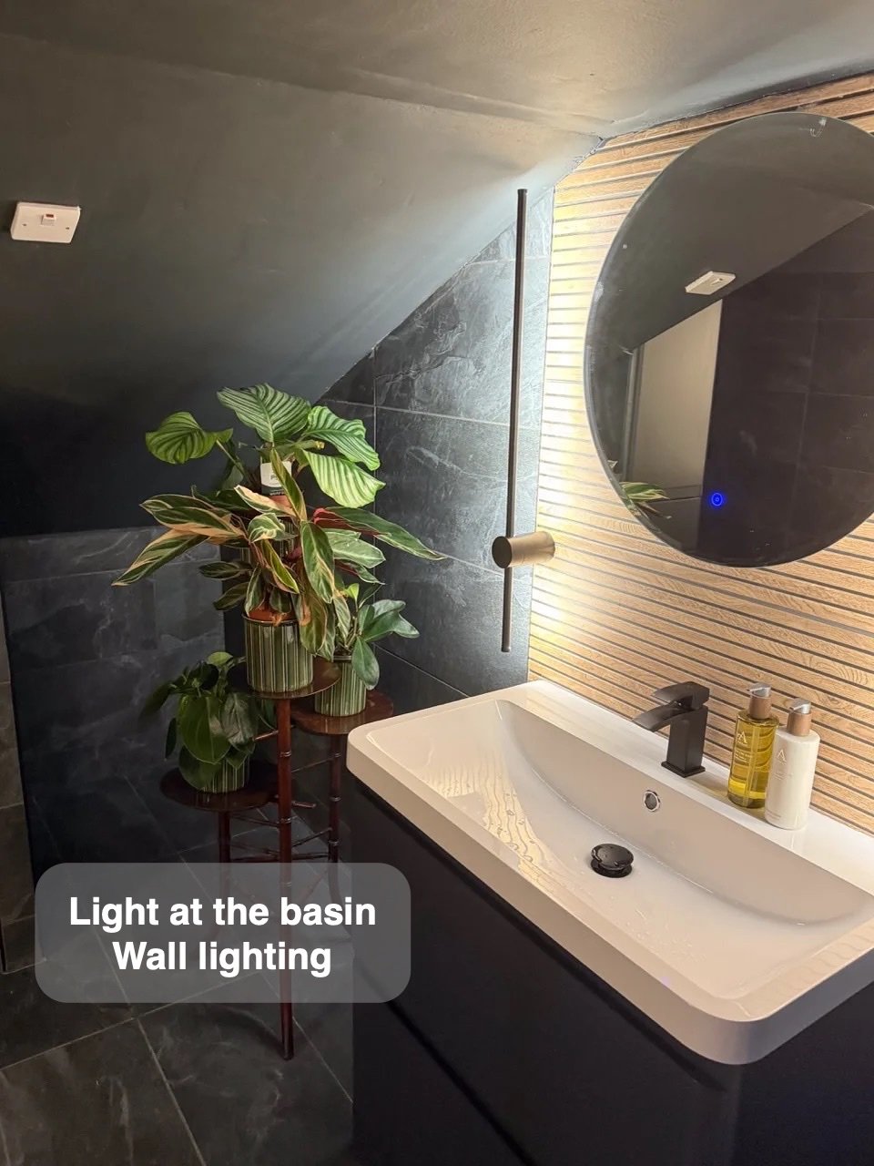Round mirror and wall light above basin