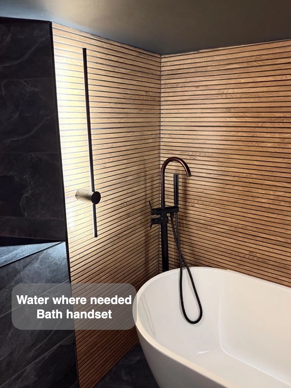 Bath handset beside wood-effect tiles