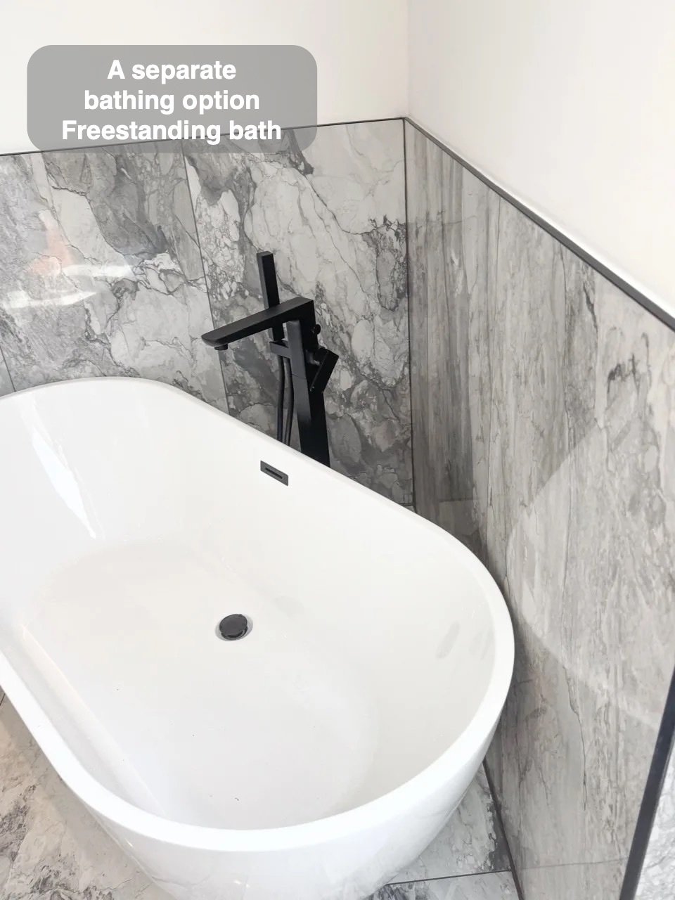 Angled freestanding bath beside black filler