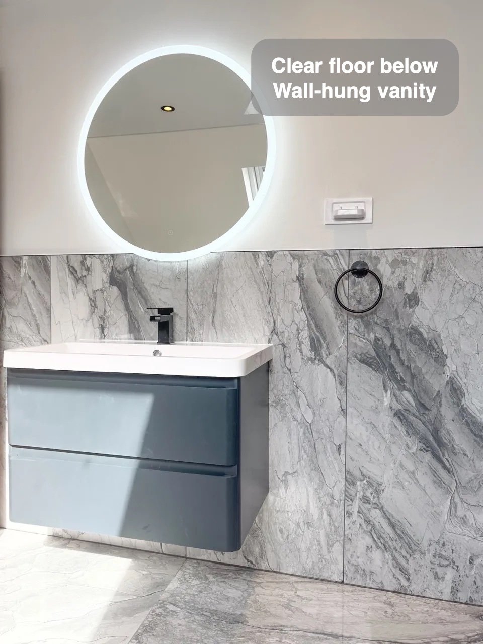 Wall-hung vanity below round illuminated mirror