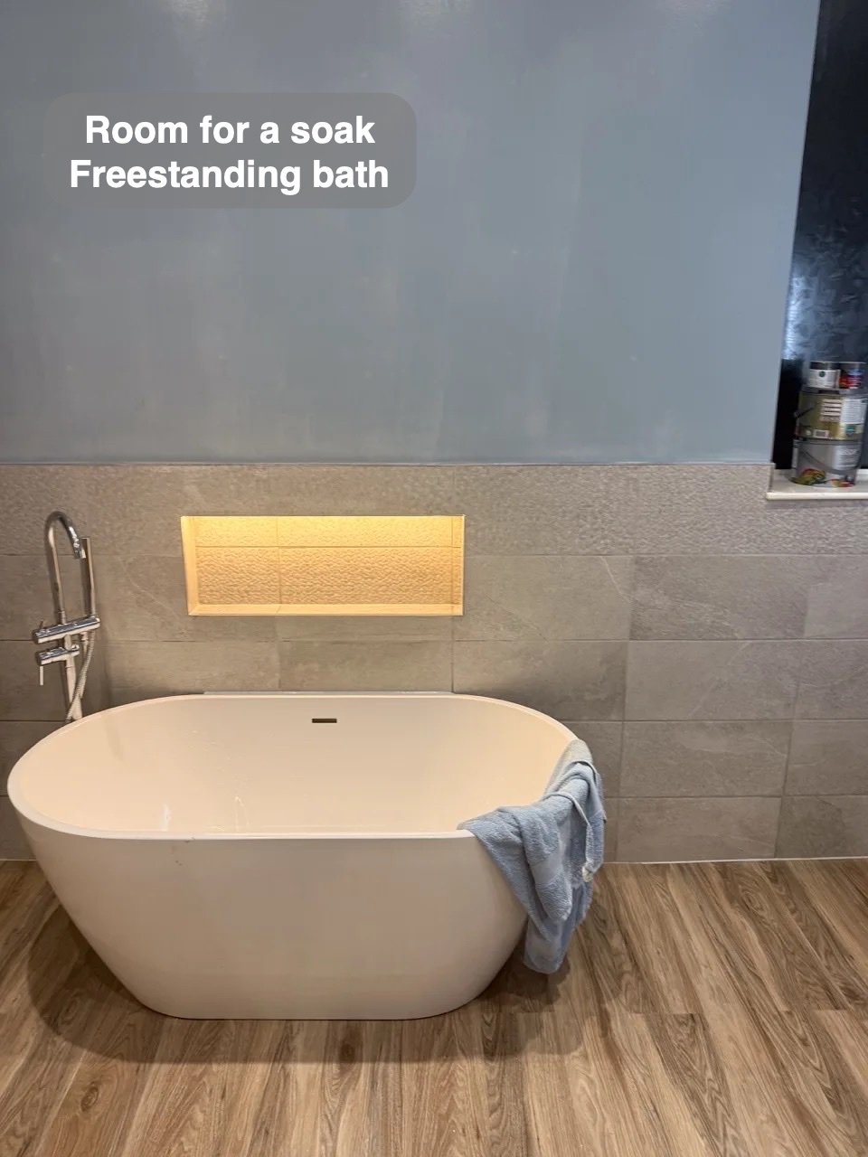 Freestanding bath below illuminated recess