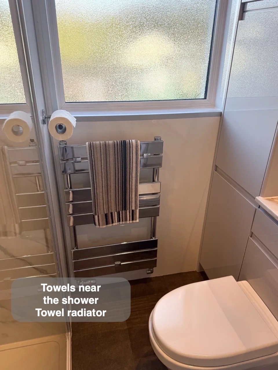 Towel radiator below window beside shower
